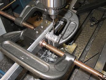 FinshedLinkage19Jan09 001 19-Jan-09 Turning our attention back to the unfinished Tumbling Shaft Levers, we re-use the tooling plate fixture to hold the levers perfectly square.  We have put two dowel pins in the plate, one for the right lever pin hole and another shorter pin that both levers have been slipped over and clamped across.  With the tooling plate clamped to an angle plate and indicated flat to the table, we can insure the Tumbling Shaft pinning holes are in line with each other.