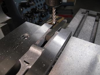RadiusRod7Jan09 010 The second step to machine the radius rod is to put a spacer in the ends of the finished 'ears' which is exactly the same width as the slot opening.  We then reclamp the part on the finished end so we can mill away the middle while securely holding it.