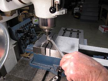 Rods14Jan09 005 Foregoing the hassle of setting up a rotary table, we clamp a dowel pin in the vise, and making sure to take light cuts and CONVENTIONAL mill only, we rotate the eccentric rod by hand and cut away the redundant nub on each rod.