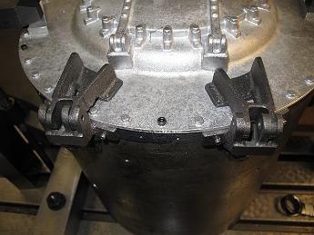 SmokeboxShellHingesMatchDrilling6-May09 001 6-May-09 With the hinge pin holes drilled in the shell hinges, we set the front cover hinges in place and using a transfer punch mark where they should be drilled.  You can also see in this picture the socket head screw we put between the two hinges.  Because our shell  hinges did not end up exactly where the print calls for them to be, our front cover hinges actually cover the two front bolt holes, rendering them ineffective. Our solution was to fill the holes with dummy bolts like the rest of the front cover has and just put one new one in the shell.