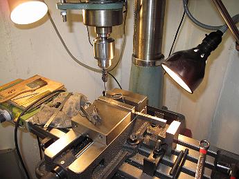 SmokeboxShellHingesMatchDrilling6-May09 002 The convenience of a second machine in the shop.  Without disturbing the setup in the big mill, we use the mill-drill to drill the front cover hinges, relying on a parallel and the flat surface of the casting for alignment.
