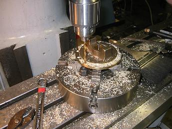 MikadoPistonCovers13Sept6 001 13-Sept-06 Drilling the bolt circle in the rear piston cover.  The only way we could hold it was to remove the 4-jaw from the lathe backing plate and bolt the chuck to the table. Using a bolt circle program on the DRO meant we did not have to revolve the cover.